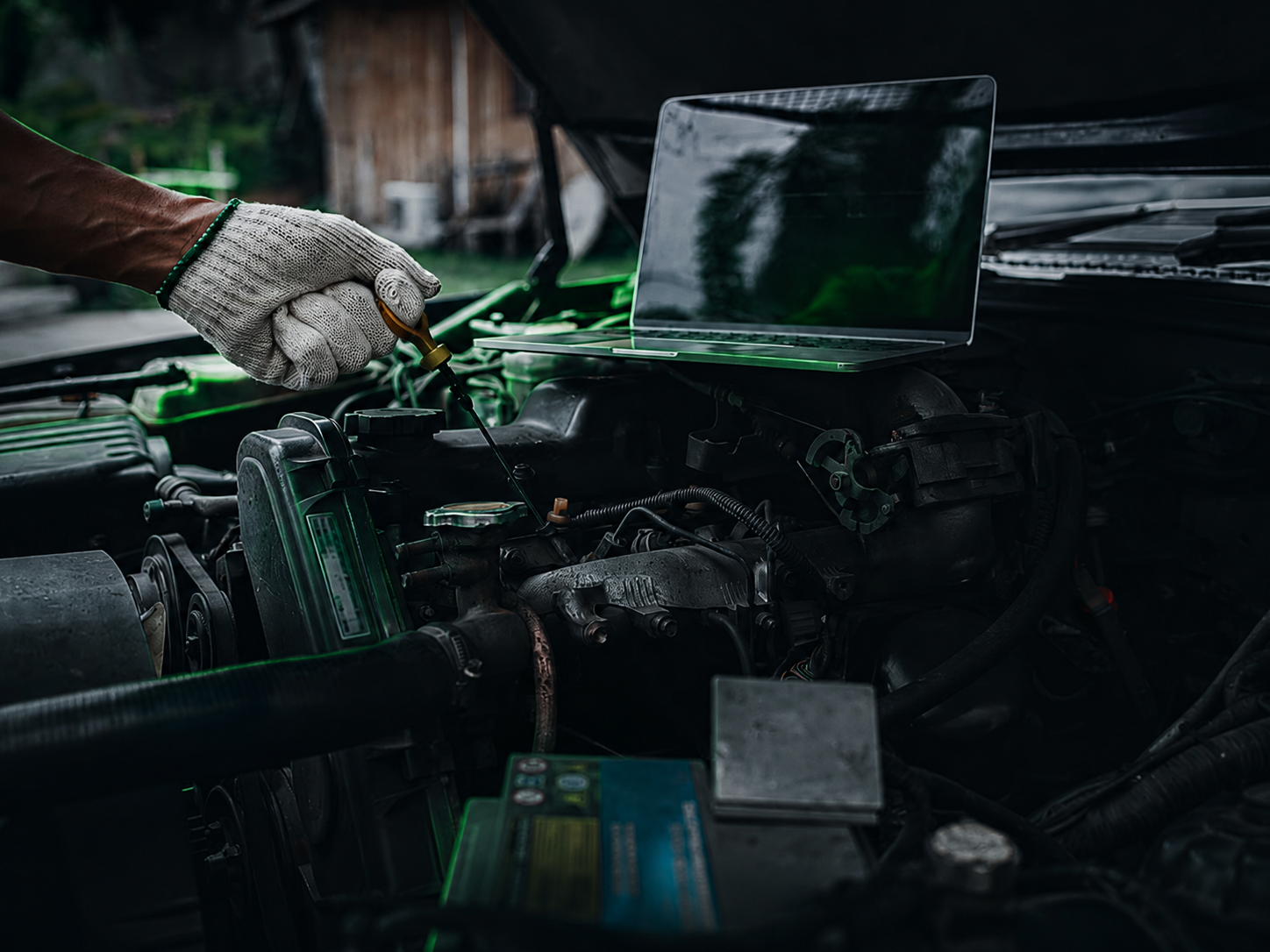 Technician working under the hood with a laptop positioned on the engine bay